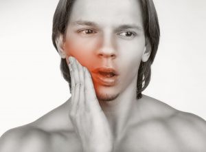 Young male holding cheek in pain sf oral surgery