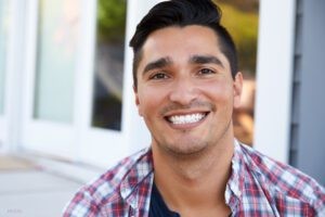 Young man in a flannel shirt with a wide and bright smile sf oral surgery